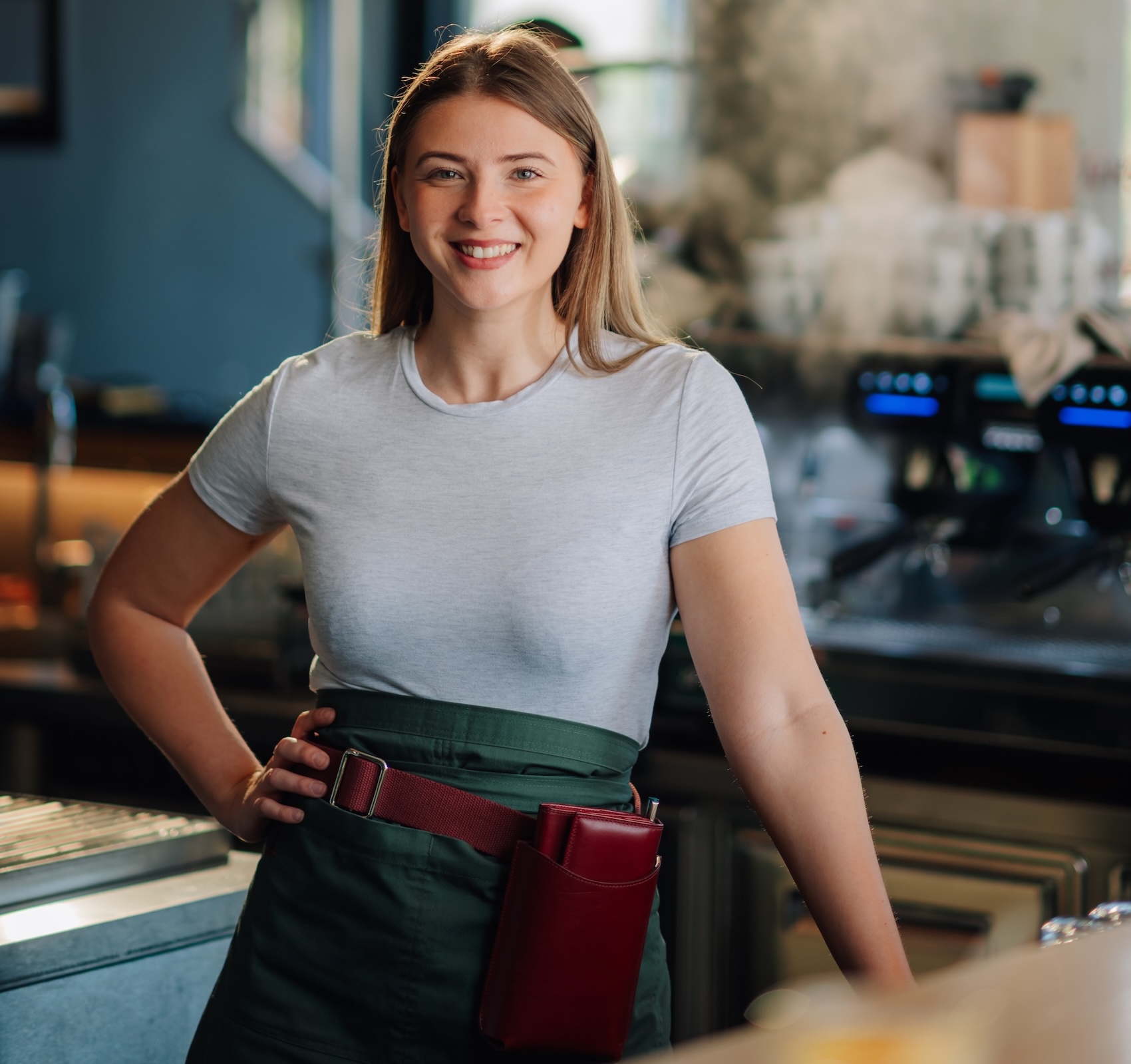 Smiling Waitress Posing In Cafe With Hand On Hip