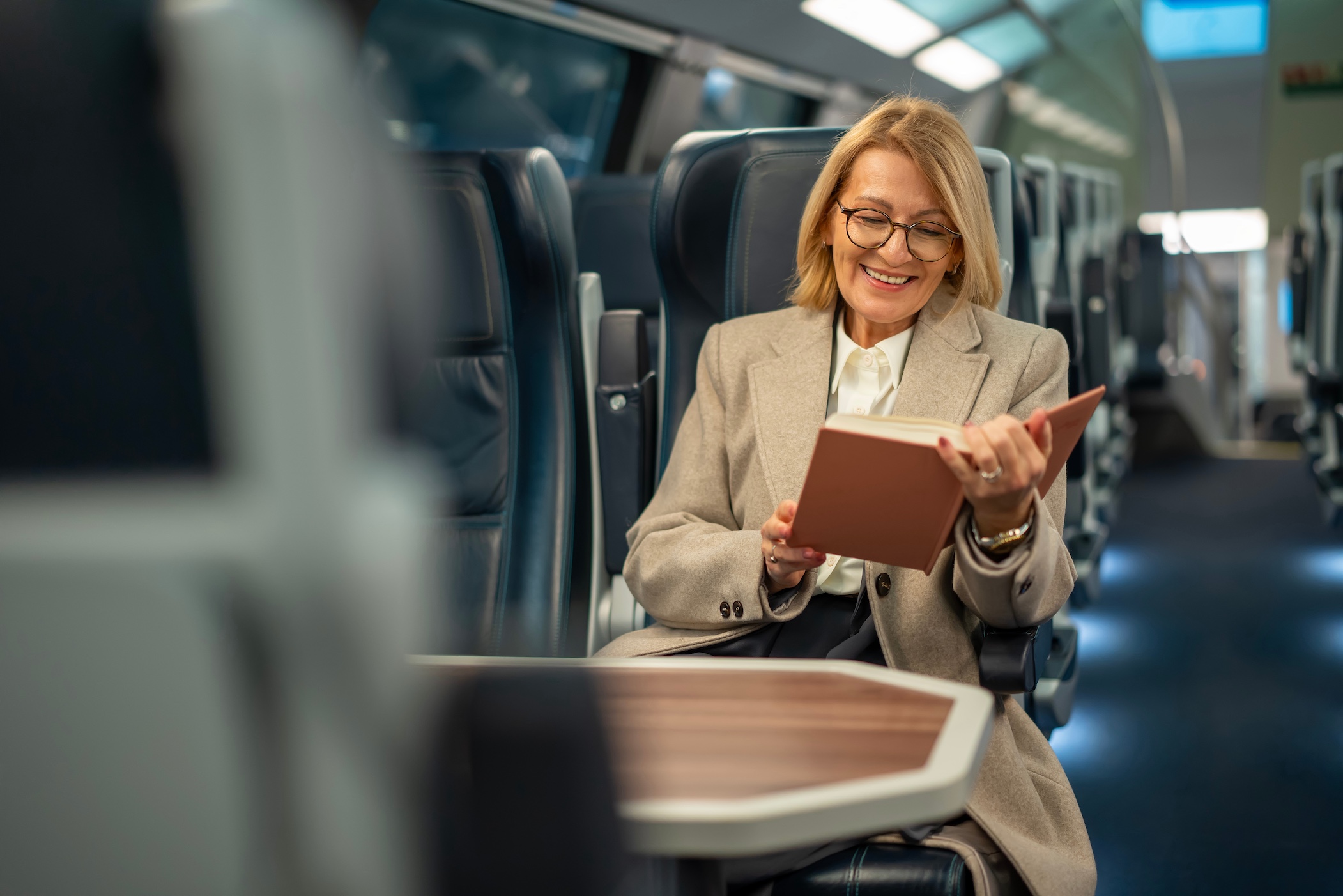 Mature Woman Enjoying Book Traveling On Modern Train