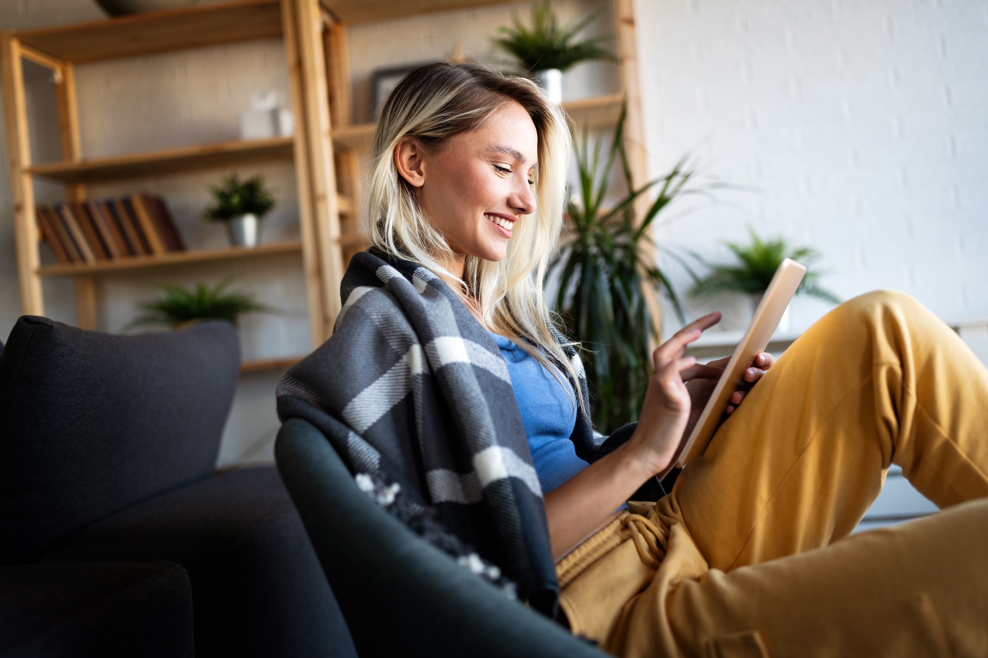 Relaxed Young Woman In Sofa Smiling Content, Happy And Reading, Working On Tablet Pc At Home