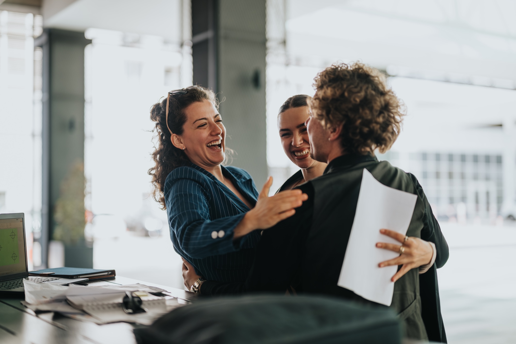 Happy Colleagues Celebrating Success With A Joyful Hug In A Modern Office Environment